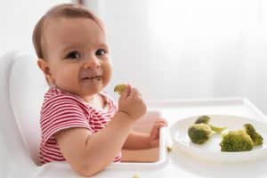 Cómo Iniciar la Alimentación Complementaria: Consejos y Recomendaciones 2 adorable bebe comiendo con sus manitas